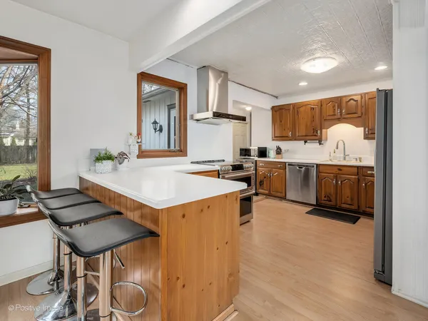 a living room with stainless steel appliances furniture a rug and a kitchen view