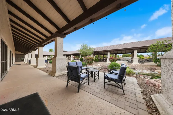 a view of a patio with dining table and chairs under an umbrella with a small garden