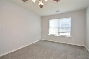 an empty room with a chandelier fan and windows