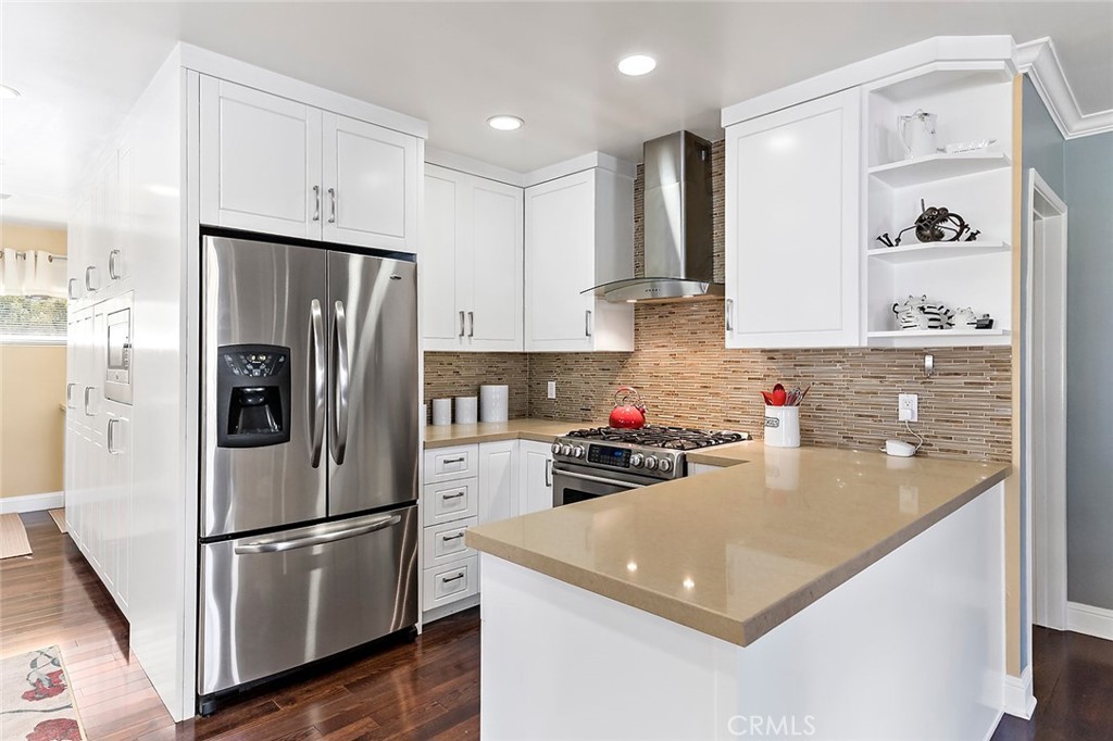 2818 Ostrom Avenue Long Beach, CA 90815 - Photo 14 of 41 a kitchen with a refrigerator a stove a sink and white cabinets with wooden floor
