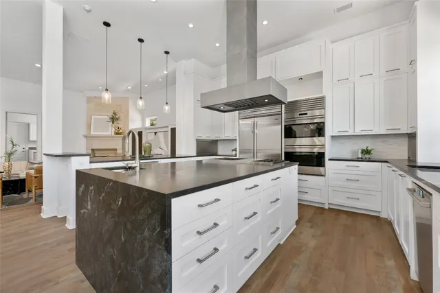 a kitchen with stainless steel appliances kitchen island granite countertop a sink a stove and a refrigerator