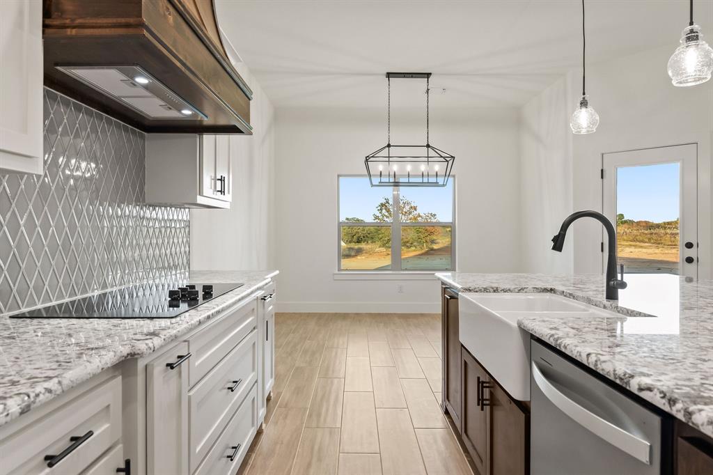 8017 Rnch Vw Place Springtown, TX 76082 - Photo 8 of 18 Galley kitchen featuring white cabinetry, quartz countertops, stainless steel appliances including a farmhouse sink, geometric tile backsplash, pendant lighting, and wood-finish flooring throughout