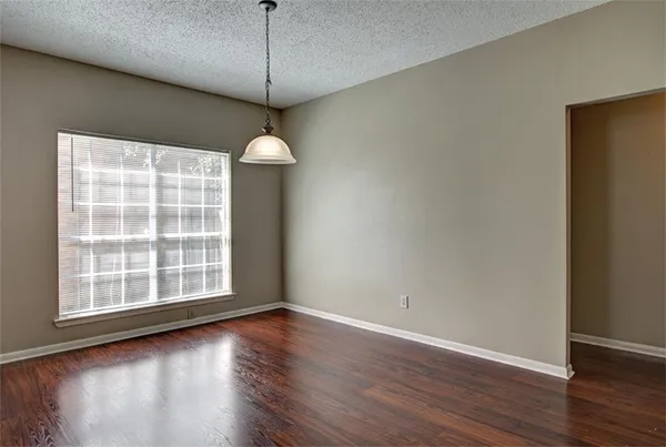 an empty room with a chandelier fan and windows