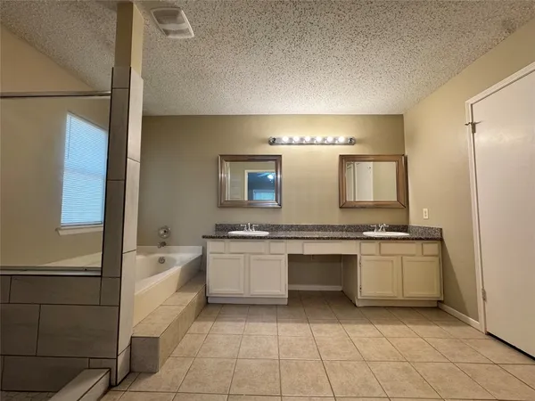 a large bathroom with a granite countertop sink a bathtub and a mirror