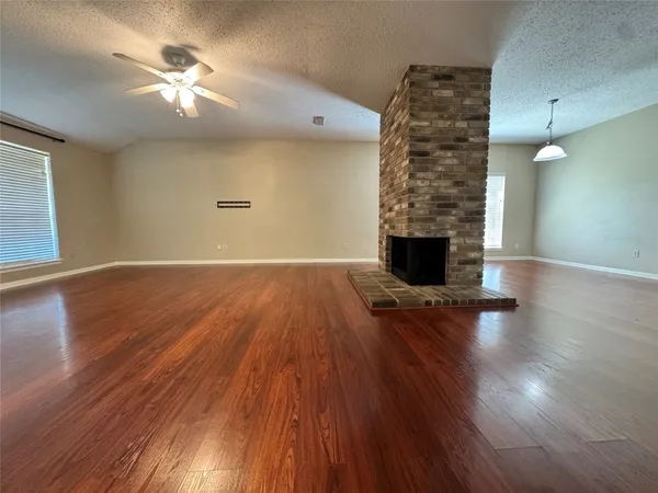 a view of an empty room with window and wooden floor
