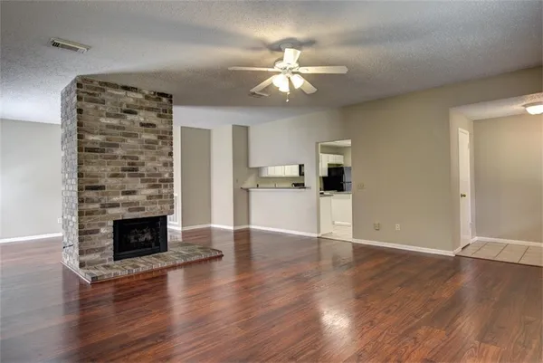 a view of an empty room with chandelier fan and fire place