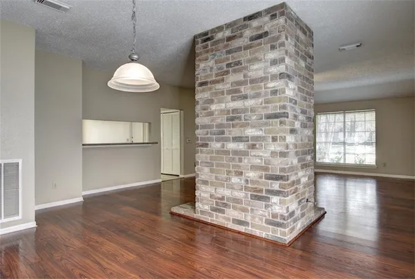 a view of an empty room with window and chandelier fan