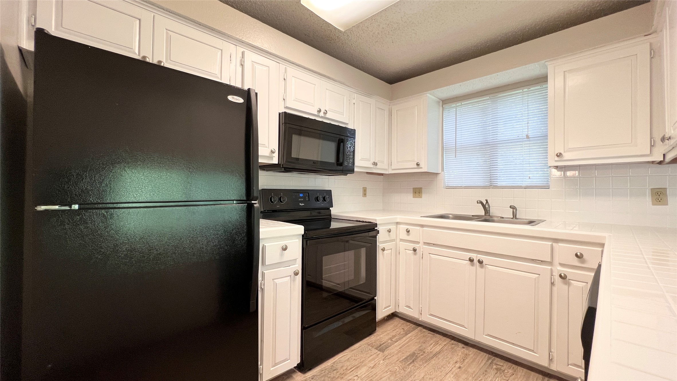 9201 Simmons Road, Unit 117 Austin, TX 78759 - Photo 6 of 20 A well-appointed kitchen features black appliances set against crisp white cabinetry and tiled countertops.