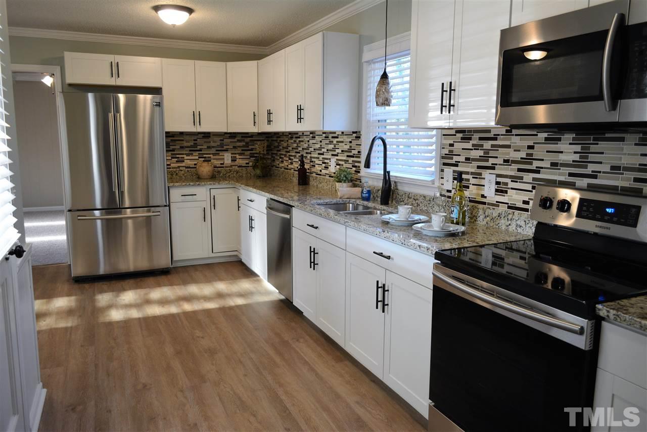 7249 Rock Service Station Road Raleigh, NC 27603 - Photo 4 of 25 Gorgeous new granite & tile backsplash, new stainless appliances, new luxury vinyl floor, new designer paint, new lighting!