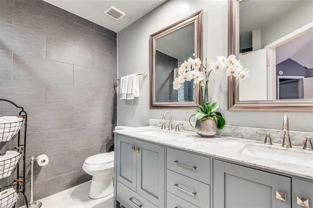 a bathroom with a granite countertop sink a toilet and mirror