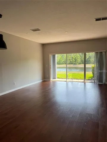 a view of an empty room with a window and wooden floor