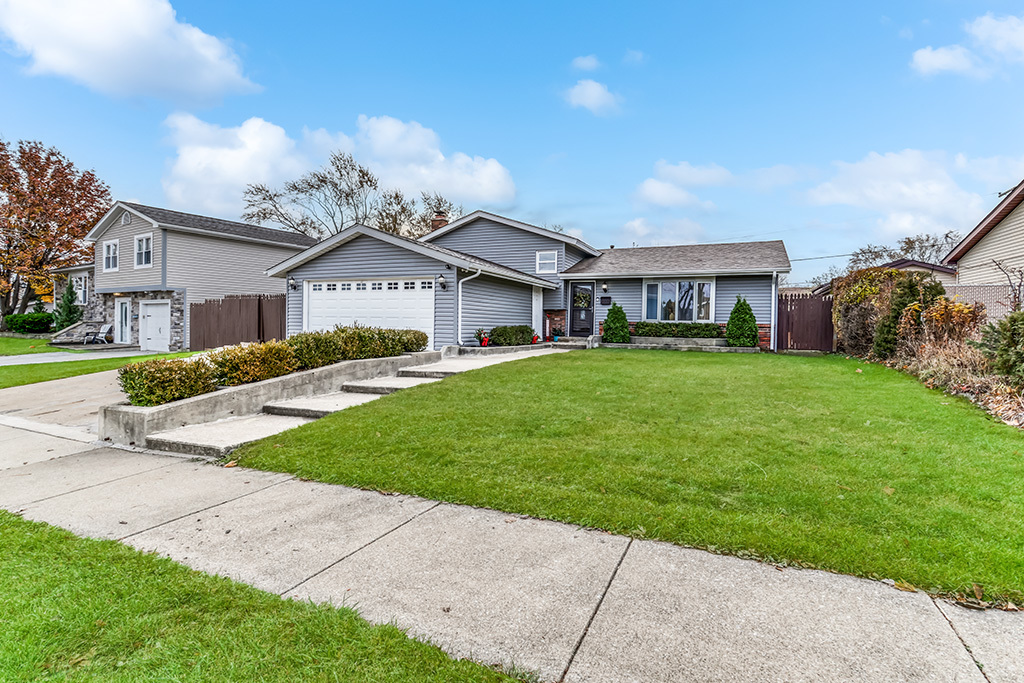 a front view of a house with a garden and trees