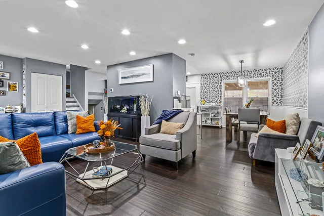 a living room with furniture kitchen view and a wooden floor