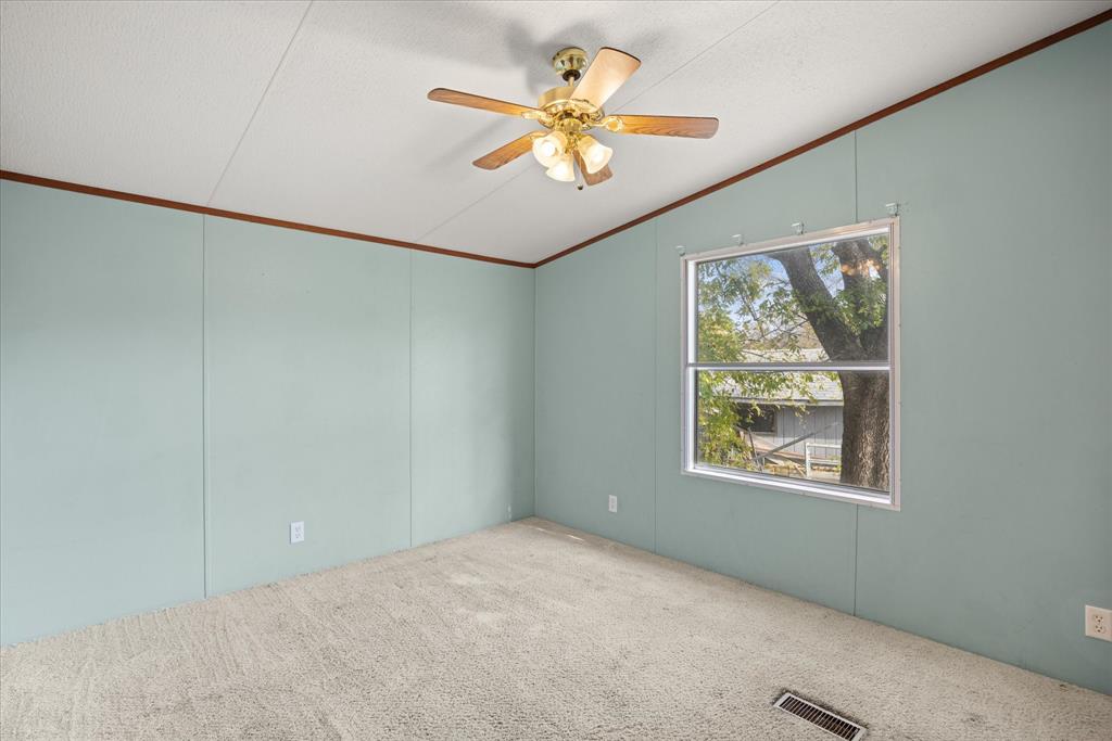 2903 Centaurus Way Granbury, TX 76048 - Photo 15 of 31 Empty room featuring vaulted ceiling, ornamental molding, carpet, ceiling fan, and a decorative wall