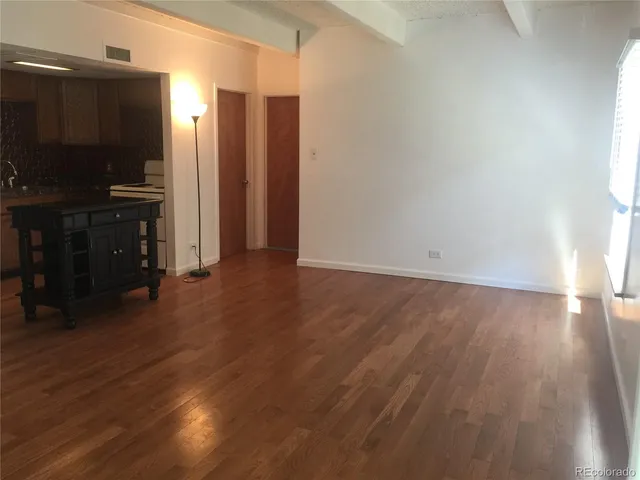 an empty room with wooden floor closet and windows