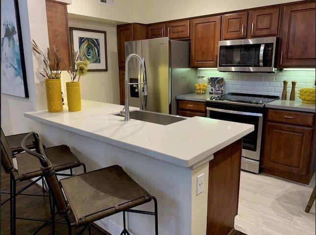a kitchen with a kitchen island a stove a sink cabinets and stainless steel appliances