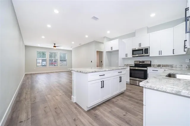 a kitchen with granite countertop a stove top oven a sink a counter space and cabinets