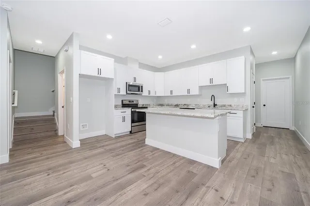 a kitchen with a refrigerator and white cabinets