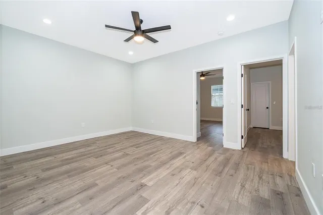 an empty room with wooden floor and a ceiling fan