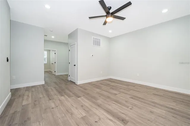 an empty room with wooden floor and a ceiling fan