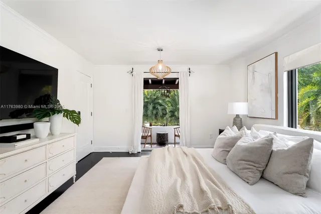 a bedroom with a large bed and a flat tv screen on dresser