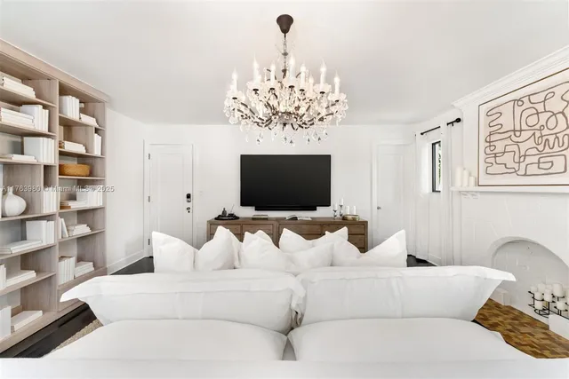 a living room with furniture a chandelier and a flat screen tv