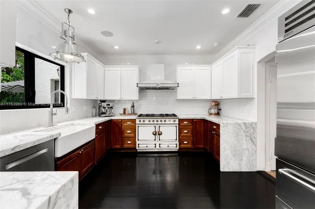 a kitchen with granite countertop a stove a sink dishwasher a refrigerator and white cabinets with wooden floor