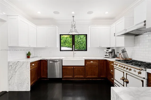 a kitchen with stainless steel appliances a sink a stove a refrigerator cabinets and a window