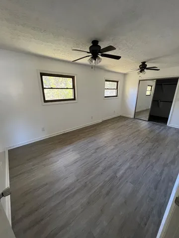 a view of a big room with wooden floor and windows