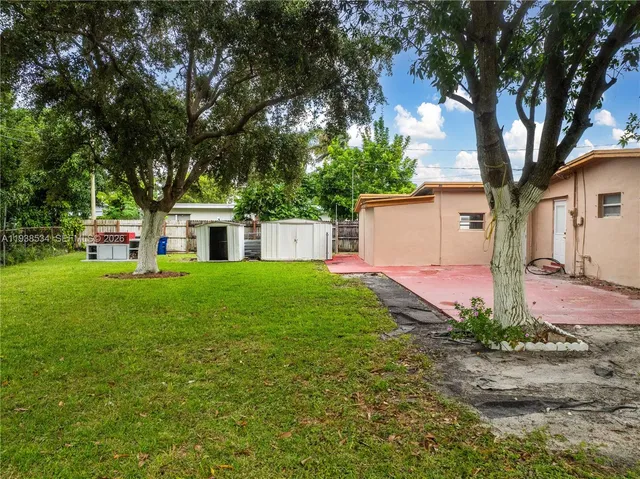 a front view of a house with garden and trees
