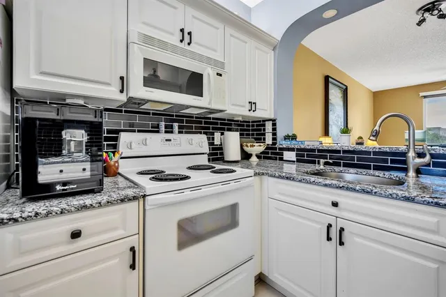 a kitchen with granite countertop white cabinets and white appliances