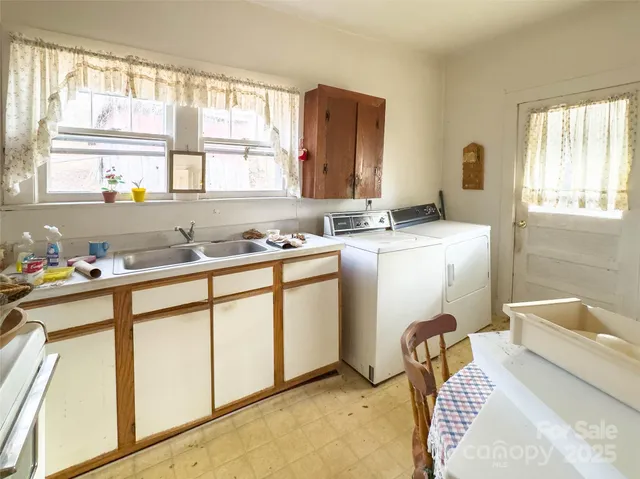 a white kitchen with a stove a sink a microwave a dining table and chairs