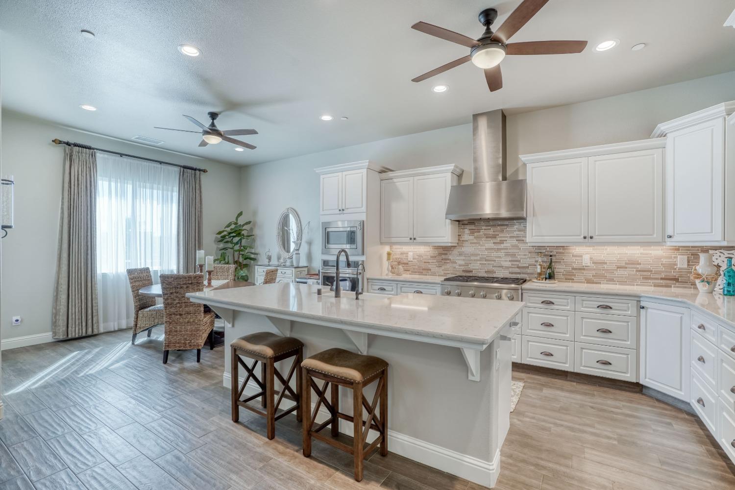 3048 Poe Avenue Clovis, CA 93619 - Photo 14 of 56 a large kitchen with kitchen island a island a sink a stove and wooden floors
