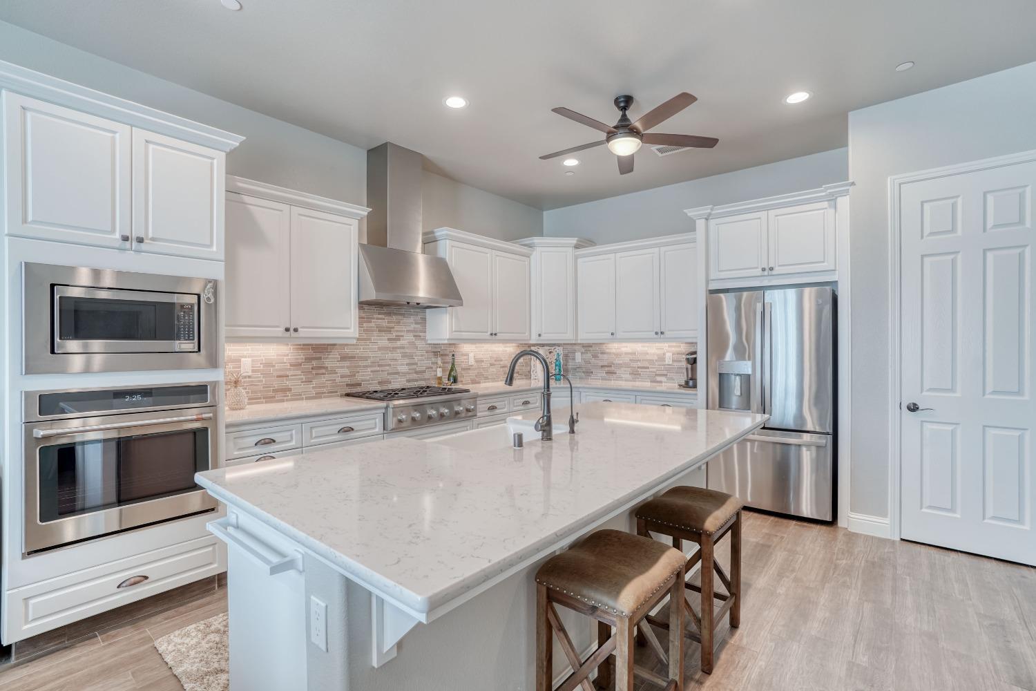 3048 Poe Avenue Clovis, CA 93619 - Photo 16 of 56 a kitchen with kitchen island a stove a sink and a refrigerator