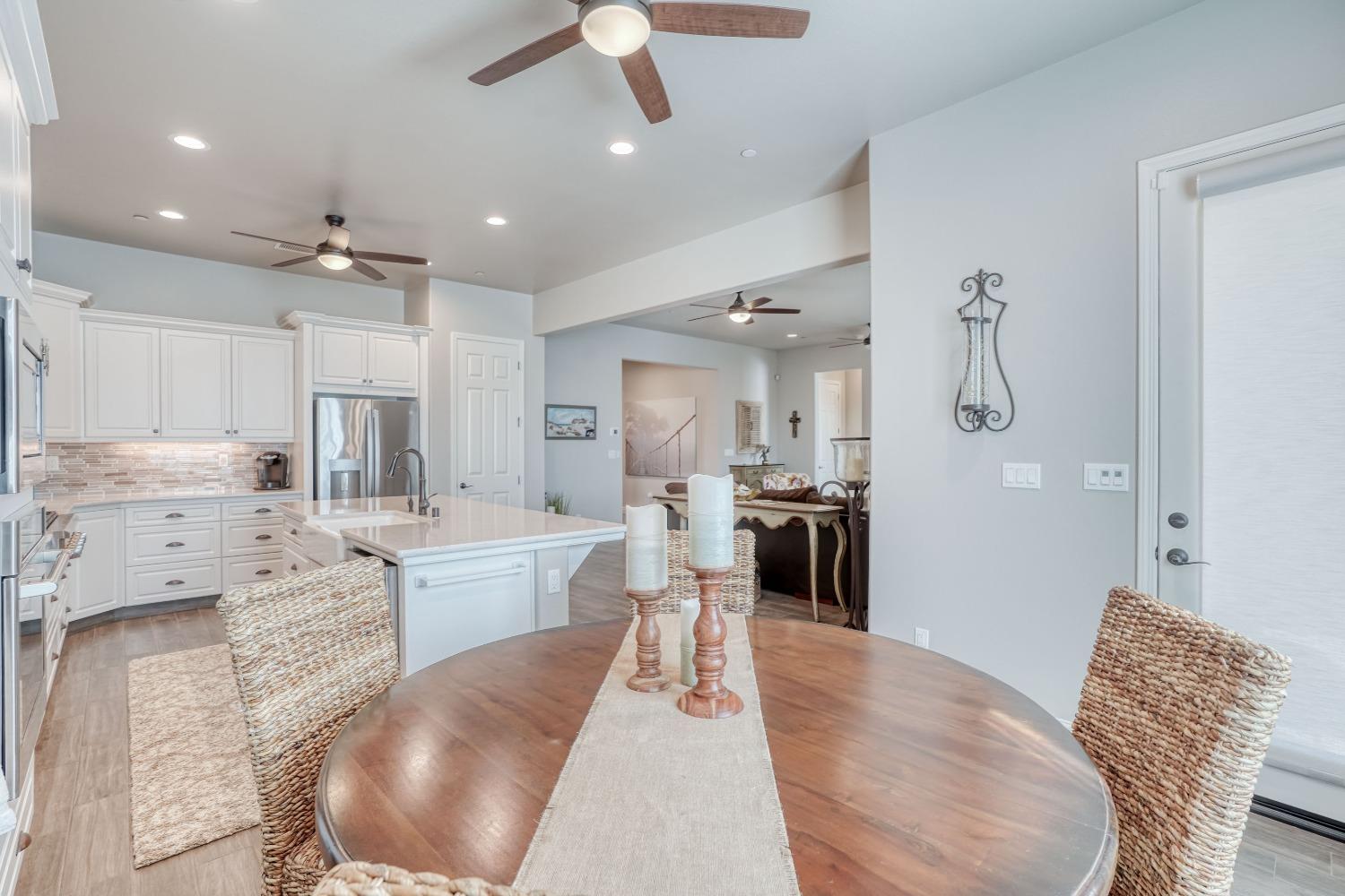 3048 Poe Avenue Clovis, CA 93619 - Photo 22 of 56 a large kitchen with kitchen island a refrigerator a stove a sink a dining table and chairs with wooden floor