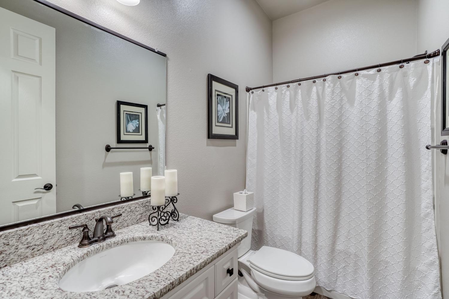 3048 Poe Avenue Clovis, CA 93619 - Photo 33 of 56 a bathroom with a granite countertop sink toilet and a mirror