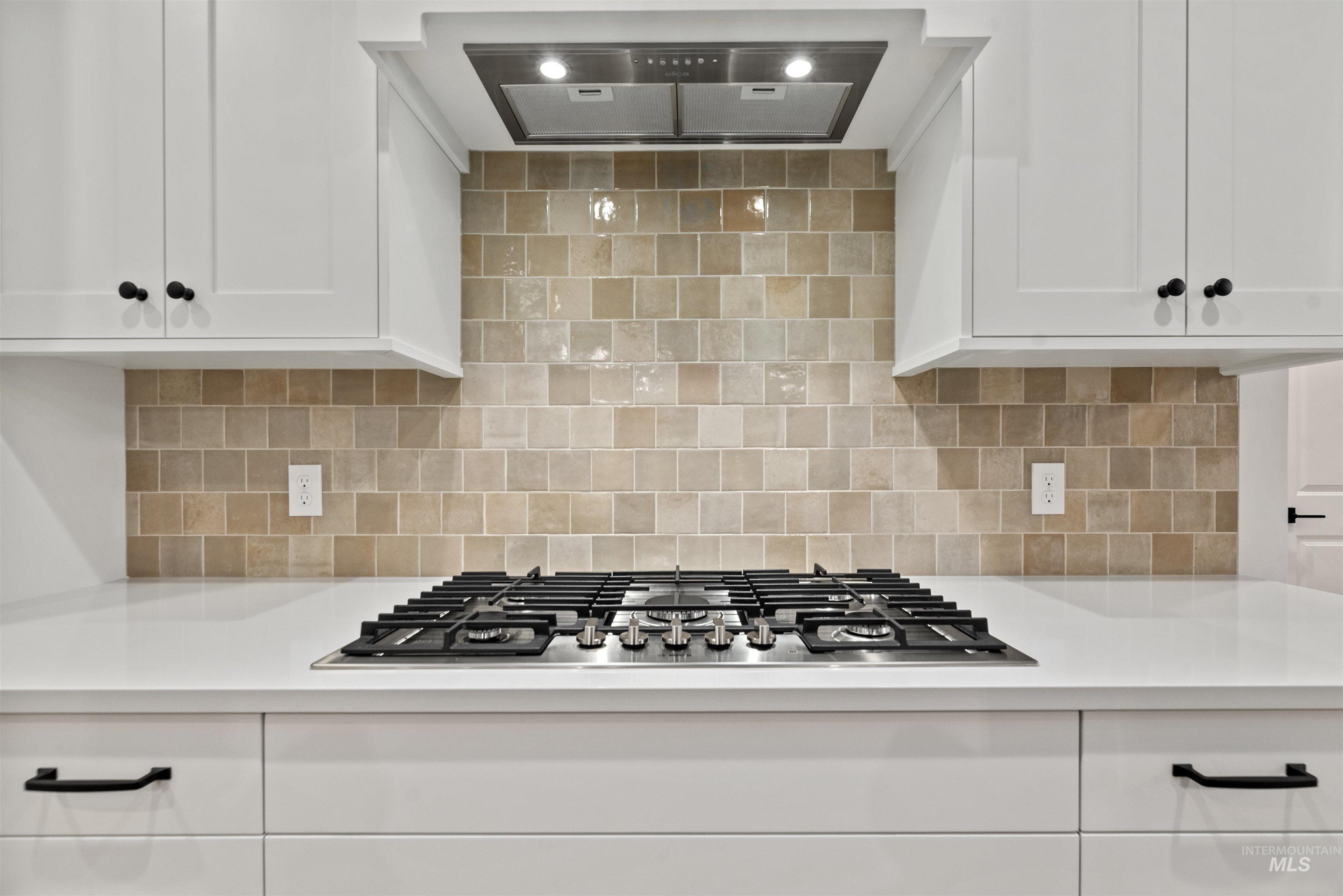 2129 East Blakehurst Street Kuna, ID 83634 - Photo 11 of 34 Kitchen featuring range hood, white cabinets, stainless steel gas stovetop, and decorative backsplash