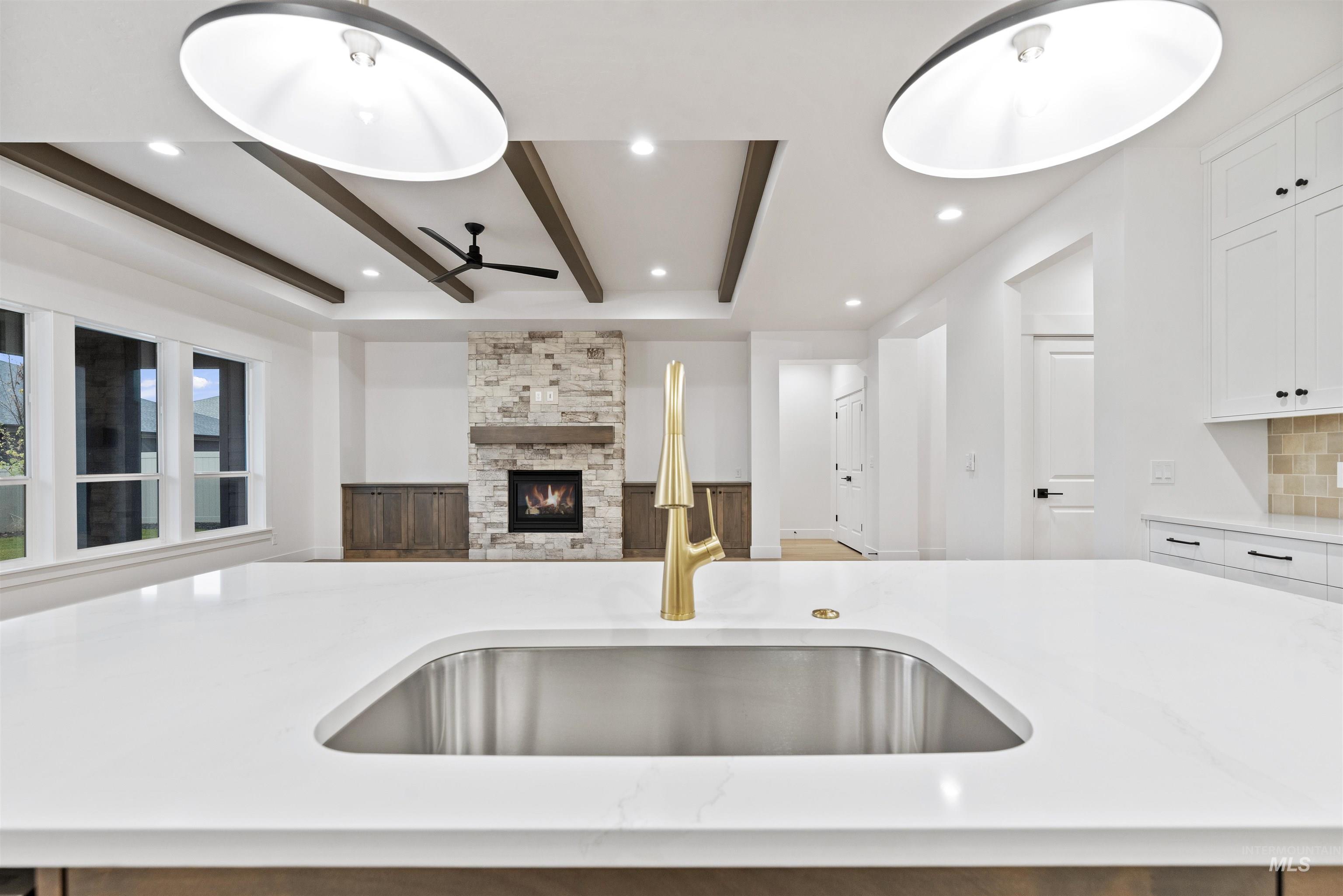 2129 East Blakehurst Street Kuna, ID 83634 - Photo 33 of 34 Kitchen featuring beamed ceiling, light stone countertops, a stone fireplace, white cabinetry, and open floor plan