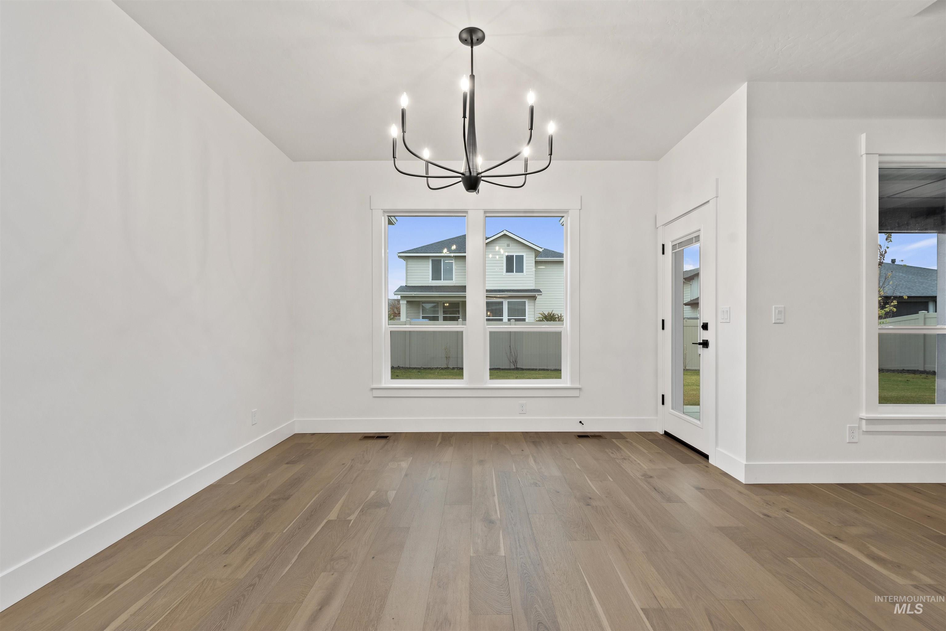 2129 East Blakehurst Street Kuna, ID 83634 - Photo 13 of 34 Unfurnished dining area featuring hardwood / wood-style flooring, a chandelier, and plenty of natural light
