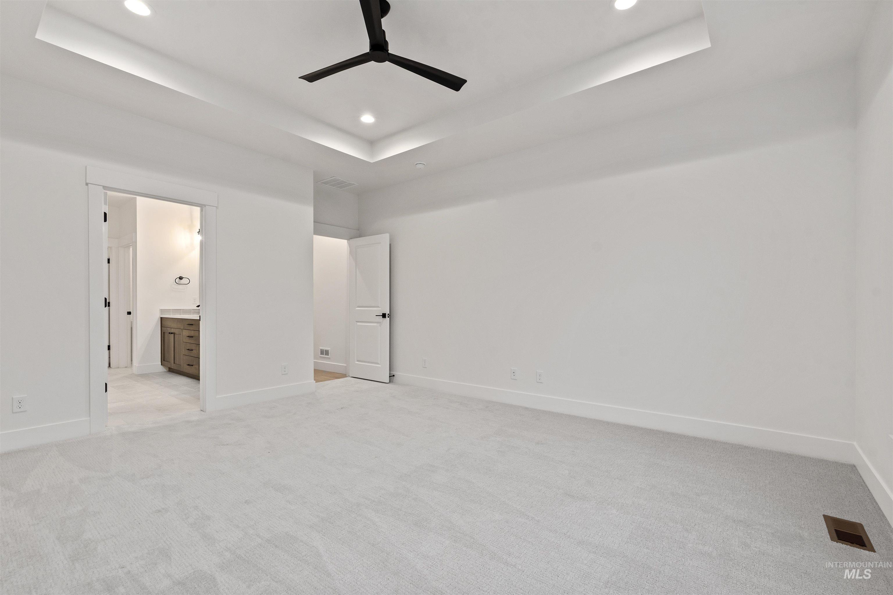 2129 East Blakehurst Street Kuna, ID 83634 - Photo 15 of 34 Unfurnished bedroom featuring a raised ceiling, recessed lighting, light carpet, ceiling fan, and ensuite bath