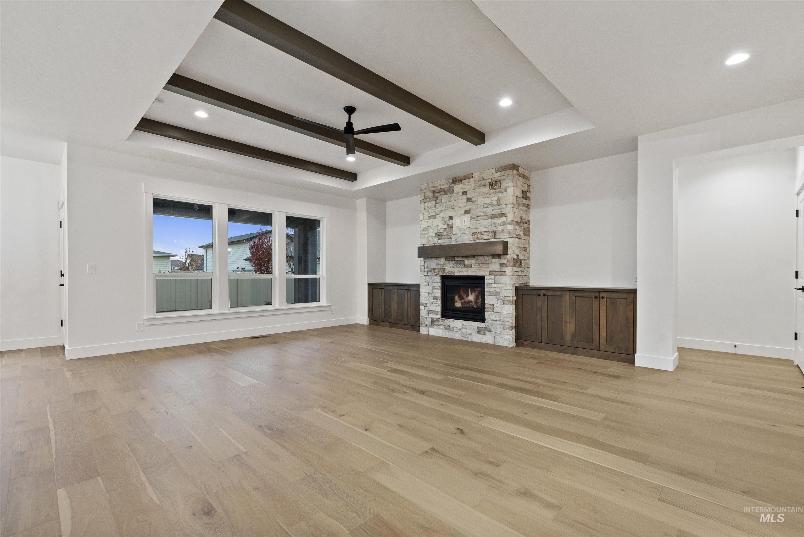 2129 East Blakehurst Street Kuna, ID 83634 - Photo 4 of 34 Unfurnished living room with ceiling fan, light wood-style floors, a fireplace, beam ceiling, and recessed lighting