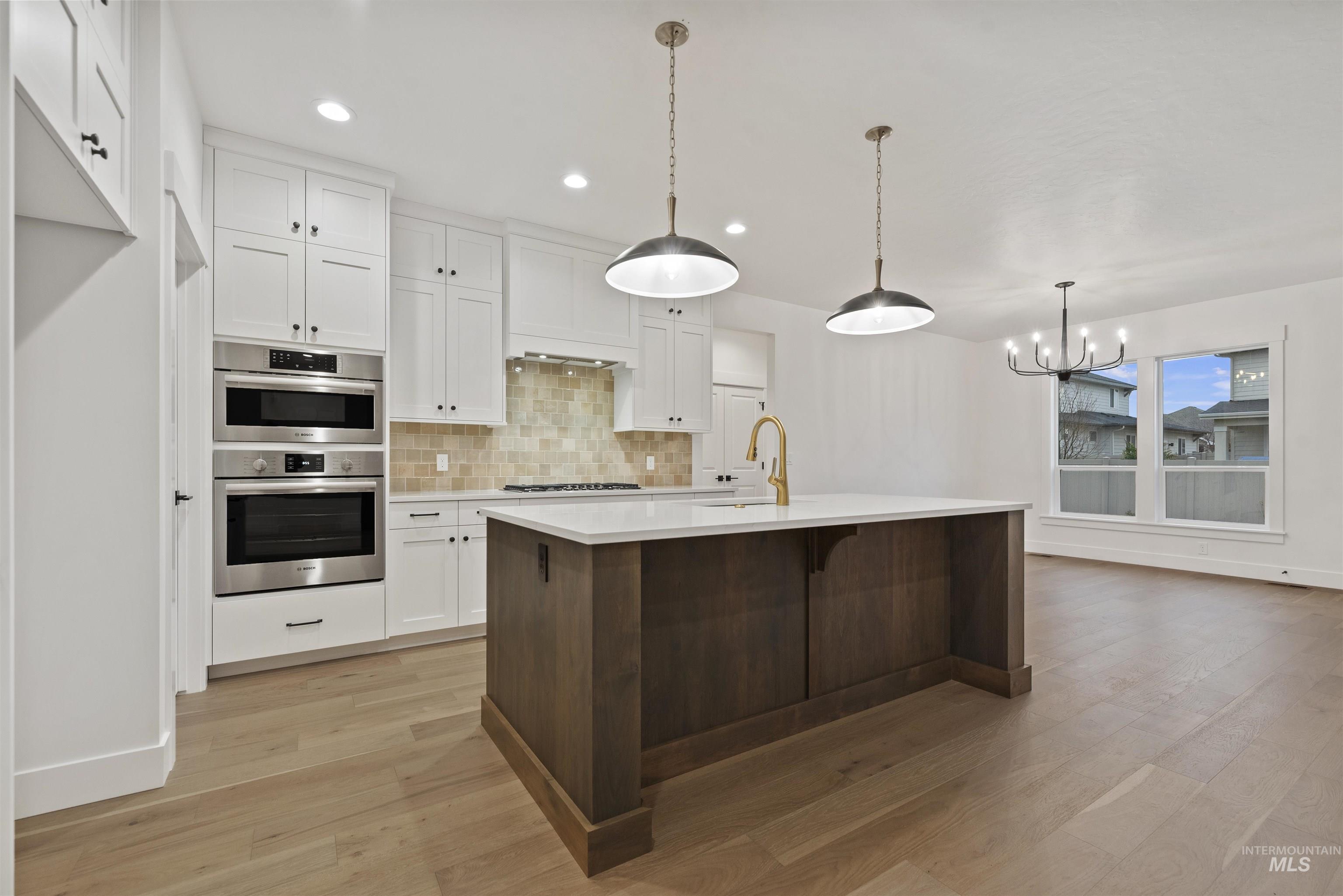 2129 East Blakehurst Street Kuna, ID 83634 - Photo 9 of 34 Kitchen featuring white cabinets, pendant lighting, decorative backsplash, a breakfast bar, and recessed lighting