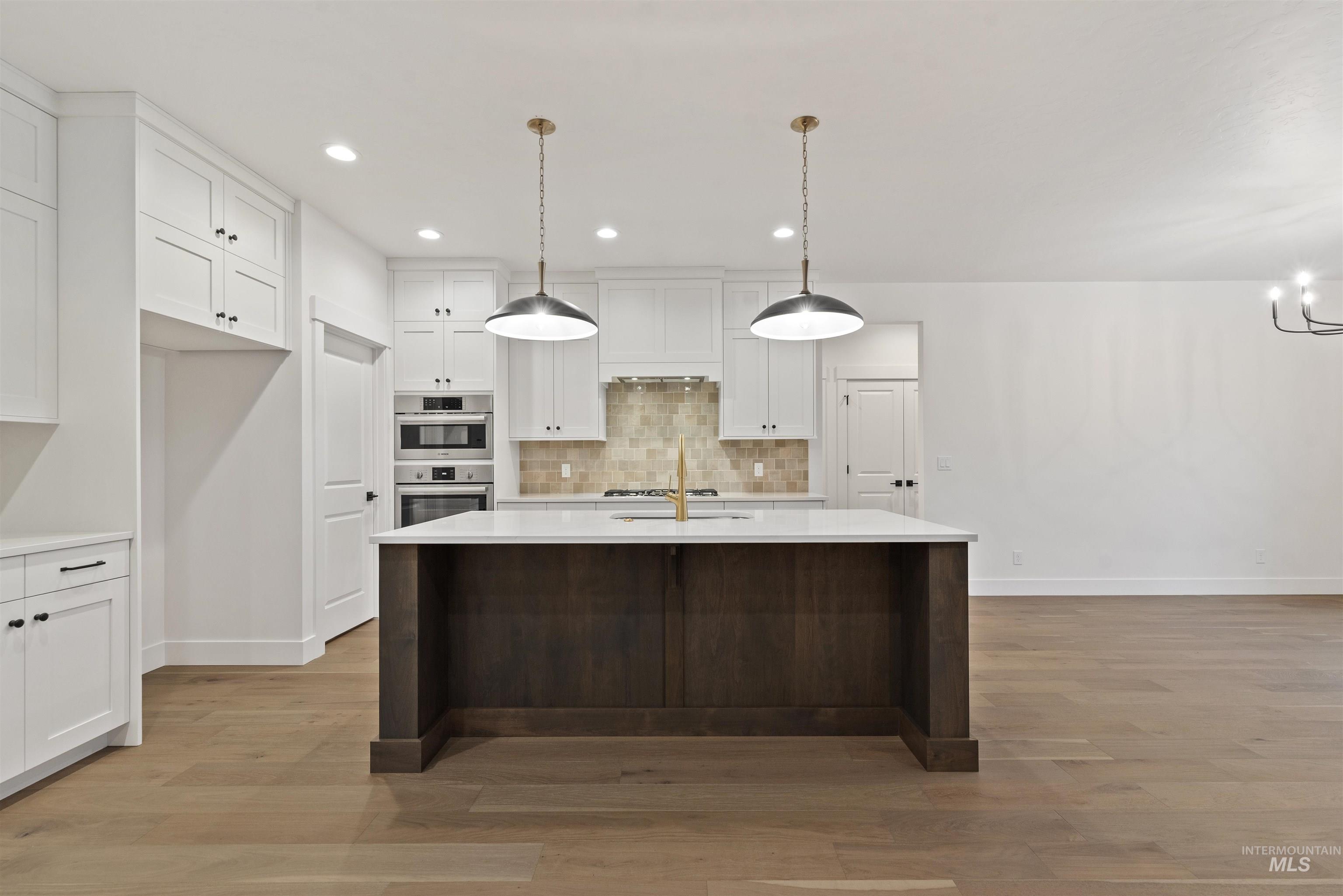 2129 East Blakehurst Street Kuna, ID 83634 - Photo 9 of 34 Kitchen with white cabinets, a kitchen island with sink, pendant lighting, recessed lighting, and light wood finished floors