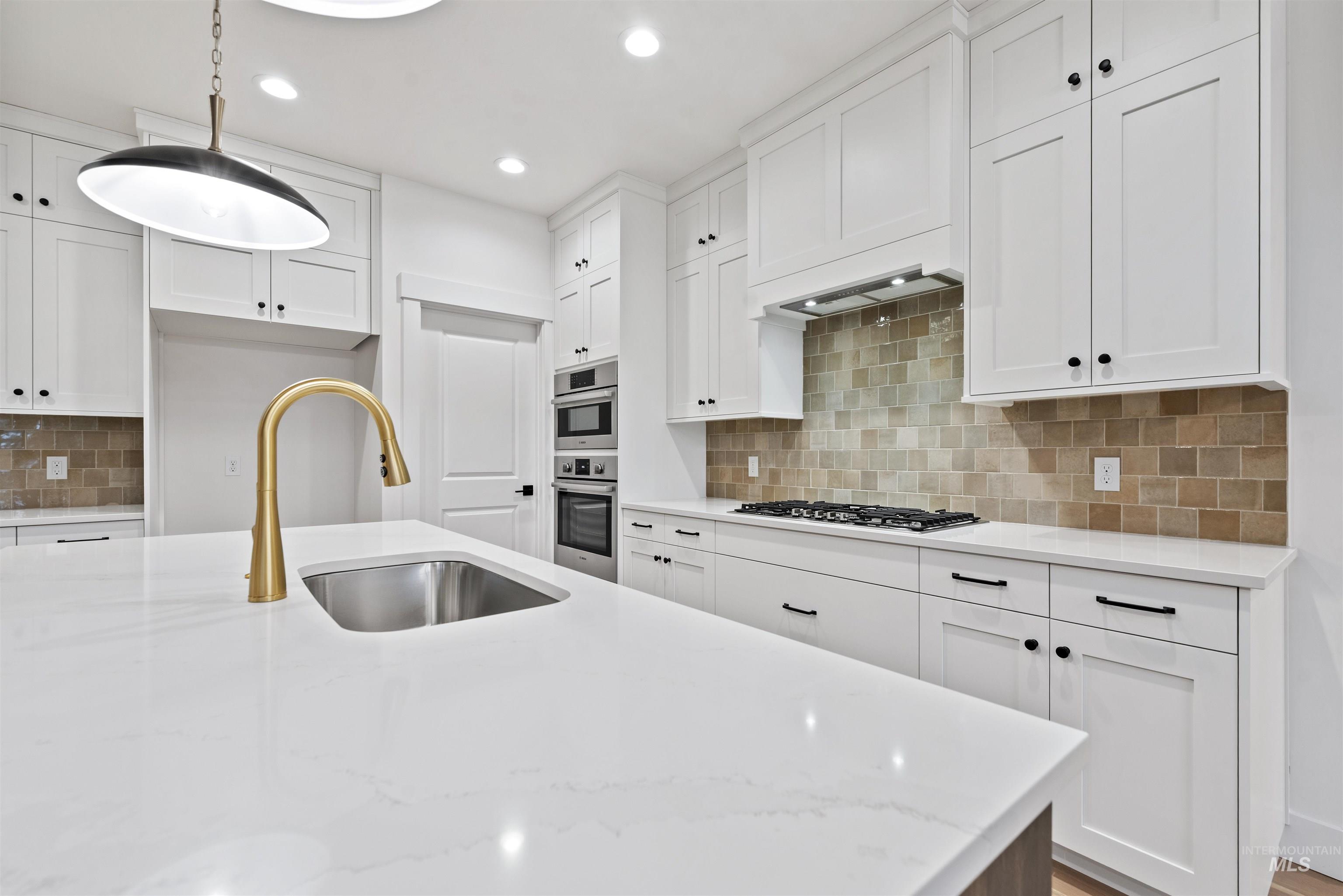 2129 East Blakehurst Street Kuna, ID 83634 - Photo 10 of 34 Kitchen with white cabinets, backsplash, light stone countertops, pendant lighting, and recessed lighting