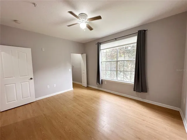 a view of an empty room with a window and wooden floor
