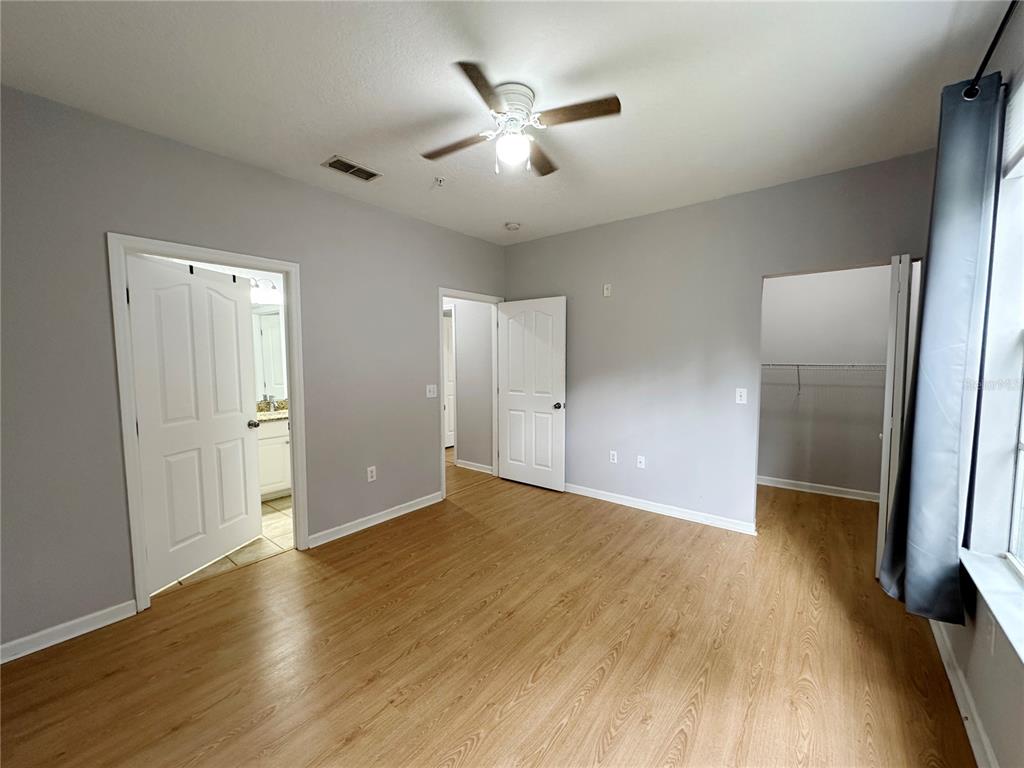 12843 Madison Pointe Circle, Unit 201 Orlando, FL 32821 - Photo 15 of 53 a view of an empty room with wooden floor and a ceiling fan