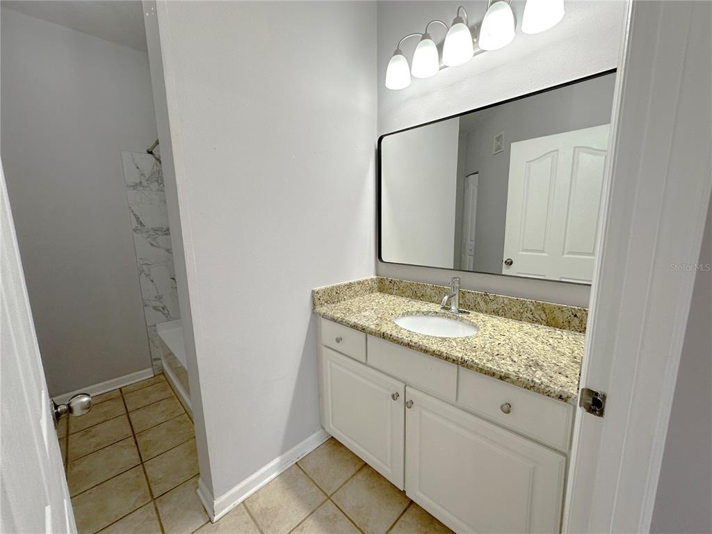 12843 Madison Pointe Circle, Unit 201 Orlando, FL 32821 - Photo 19 of 53 a bathroom with a granite countertop sink and a mirror