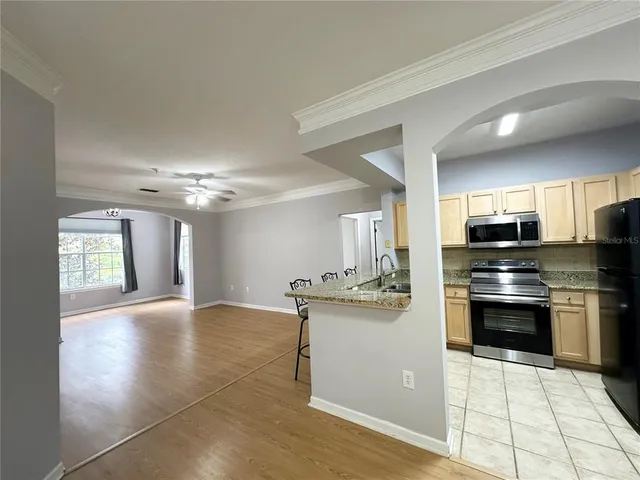 a kitchen with stainless steel appliances granite countertop a stove top oven a sink dishwasher and a refrigerator with wooden floor