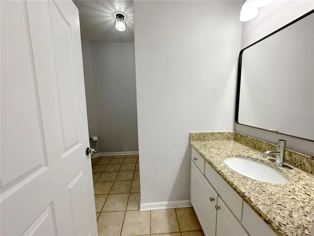 a bathroom with a granite countertop sink a toilet and a mirror