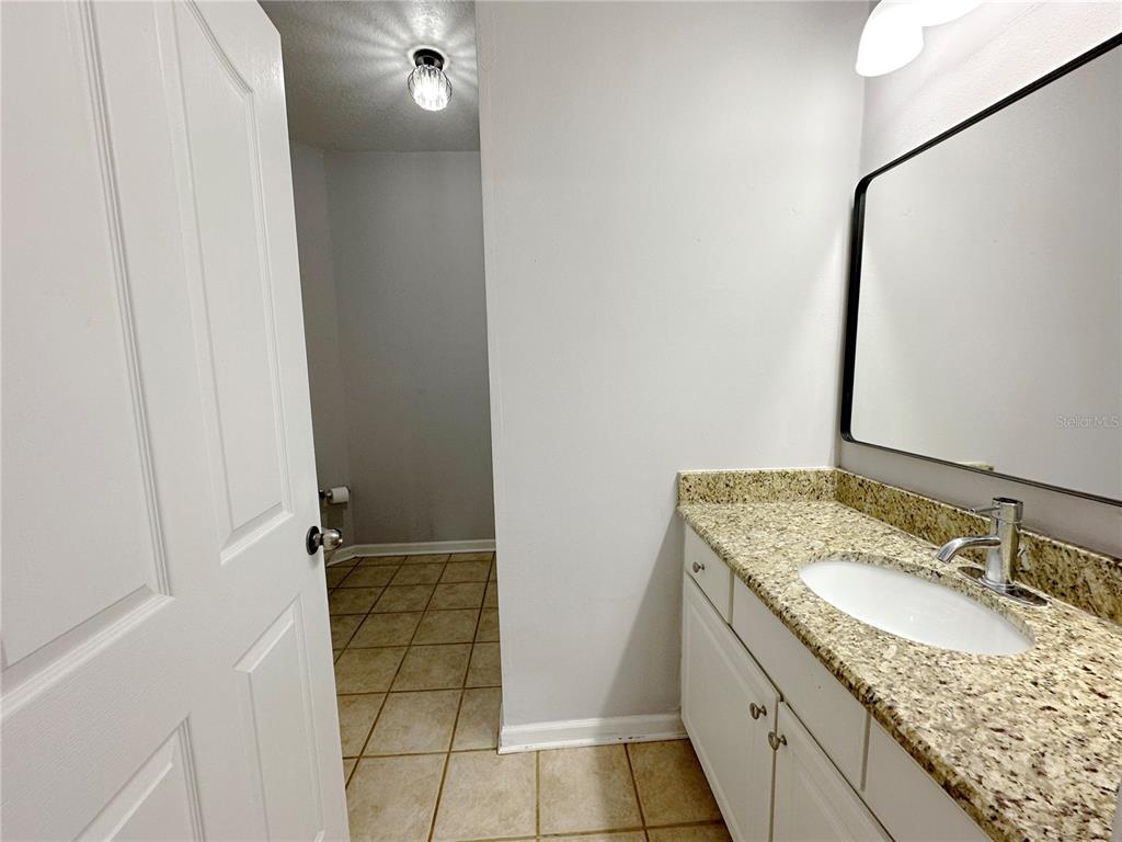 12843 Madison Pointe Circle, Unit 201 Orlando, FL 32821 - Photo 23 of 53 a bathroom with a granite countertop sink a toilet and a mirror